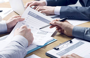 Business professionals working together at office desk, hands close up pointing out financial data on a report