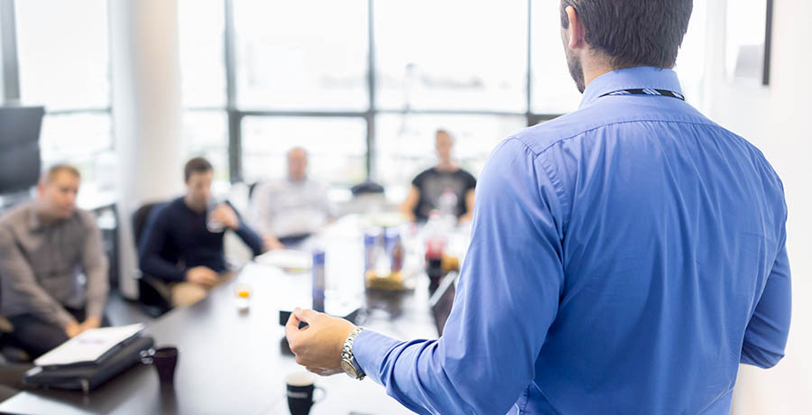 Business presentation on corporate meeting. Business man making a presentation at office. Business executive delivering a presentation to his colleagues during meeting or in-house business training, explaining business plans to his employees.