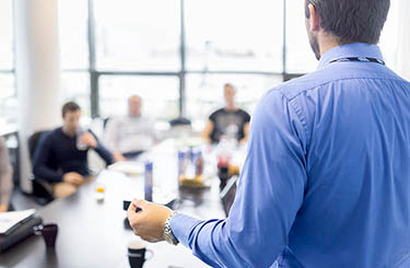 Business man making a presentation at office. Business executive delivering a presentation to his colleagues during meeting or in-house business training, explaining business plans to his employees.